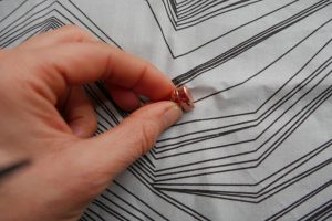 Zipper, Häkchen verhindert, dass sich der Schieber selbstständig in Öffnungsrichtung bewegt und der Reißverschluss sich selbstständig öffnet